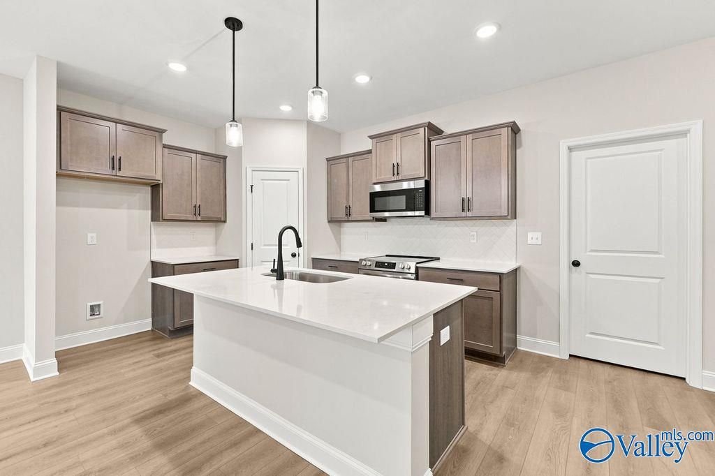 Modern kitchen with white island, quartz countertops, and cabinets in The Camilla C floor plan at The Retreat, Hartselle.