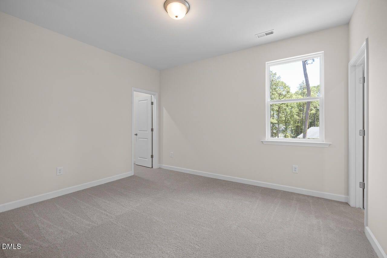 Spacious secondary bedroom with neutral carpet and natural light in The Hickory II B floor plan, Montrose, Aberdeen, NC.