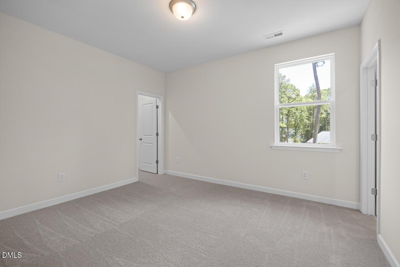 Spacious secondary bedroom with neutral carpet and natural light in The Hickory II B floor plan, Montrose, Aberdeen, NC.