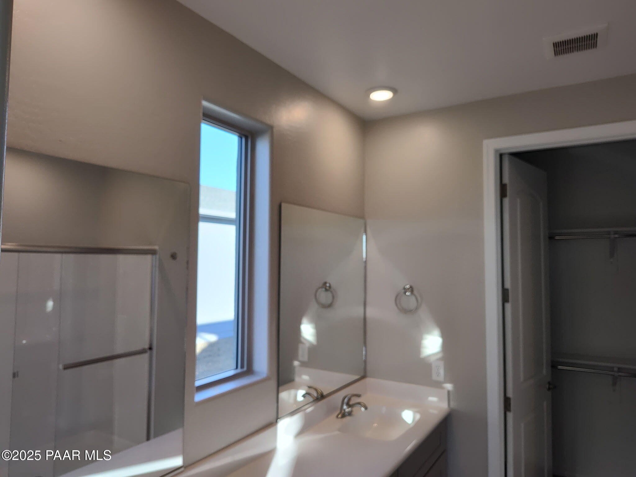 Elegant master bathroom with vanity sink, glass shower enclosure, and walk-in closet in Davidson Homes The Frontier C, Prescott Valley