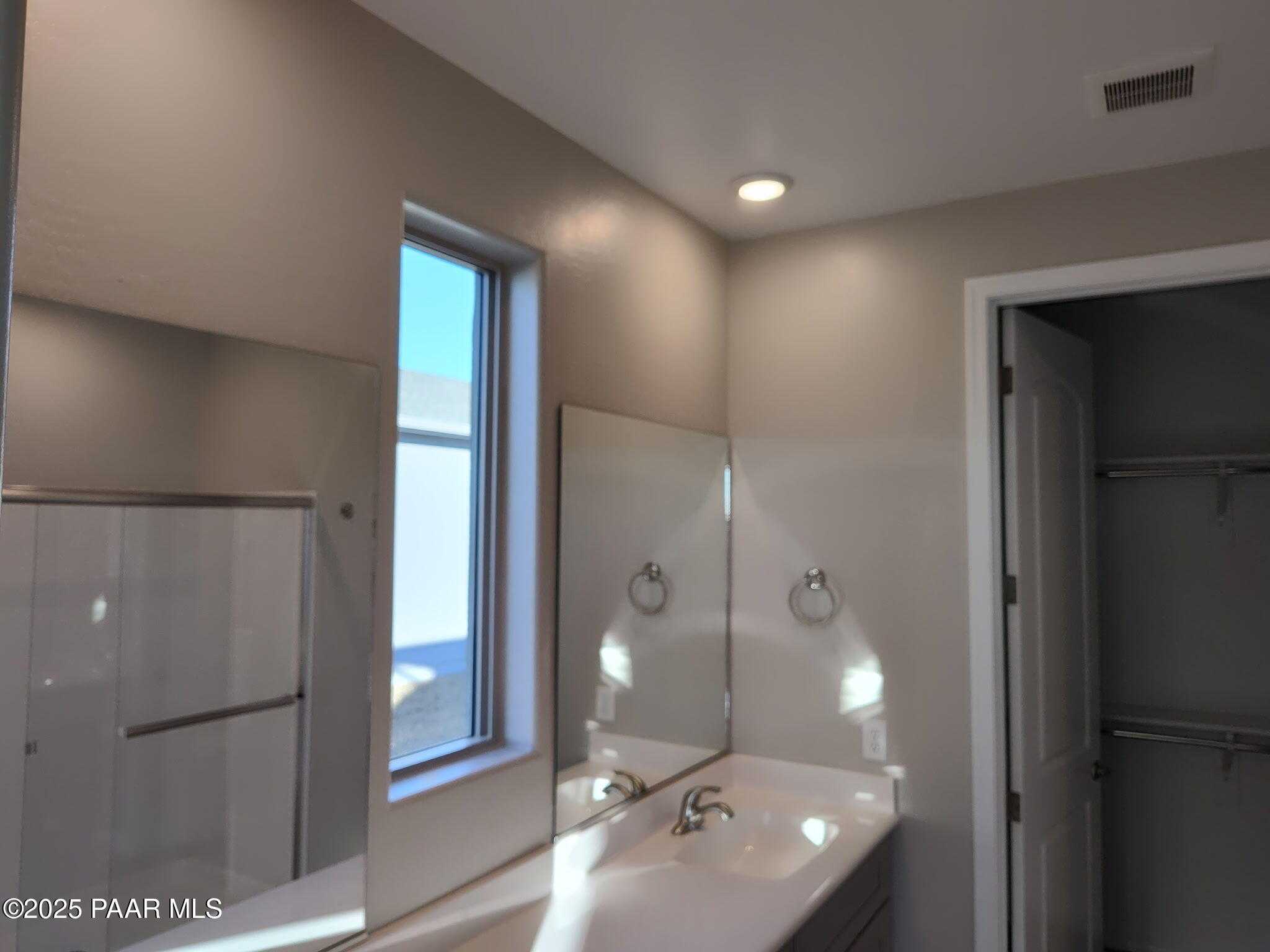 Elegant master bathroom with vanity sink, glass shower enclosure, and walk-in closet in Davidson Homes The Frontier C, Prescott Valley