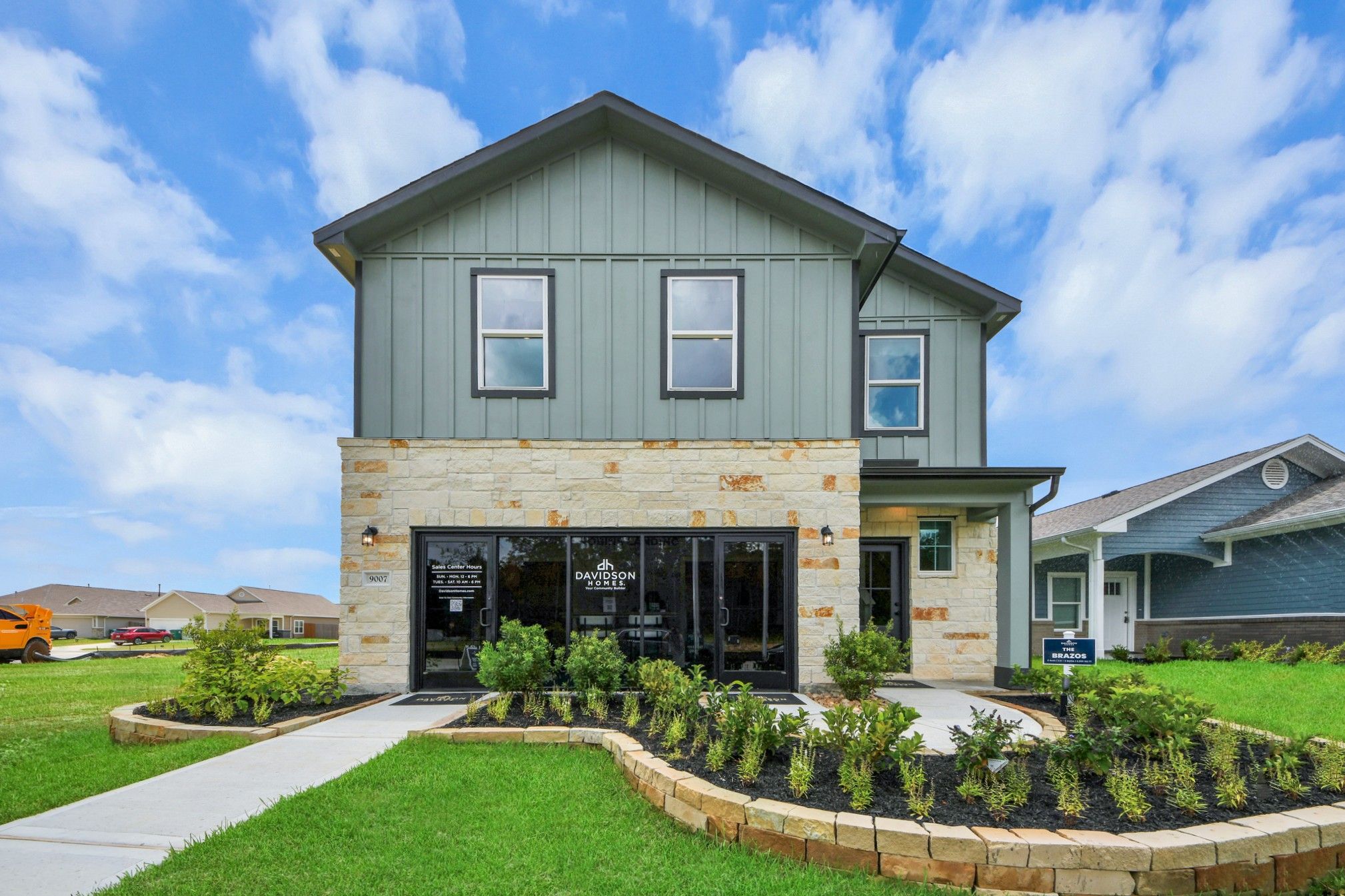 Happy family forming house shape with arms on gray sofa in modern Robins Landing living room, Houston Texas by Davidson Homes