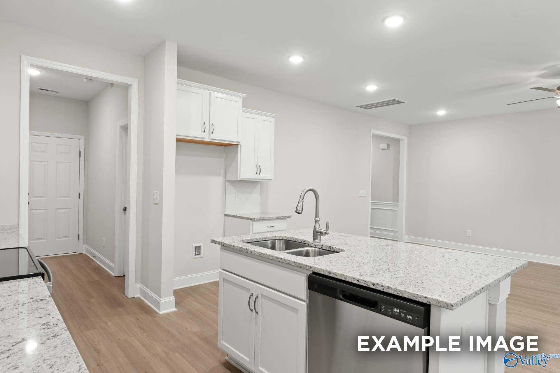 Modern kitchen with white shaker cabinets, granite island, stainless sink in The Camden C 3-bedroom home, Pavilion, Huntsville AL