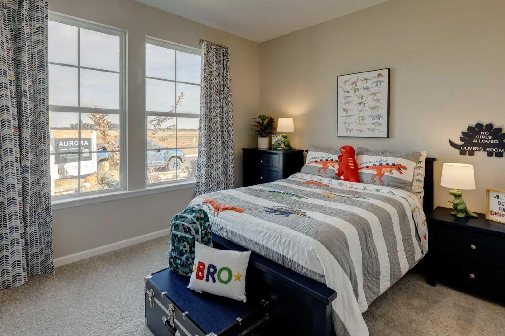 Cozy dinosaur-themed boy's bedroom in The Aurora B with striped bedding, red toy dino, posters, and windows