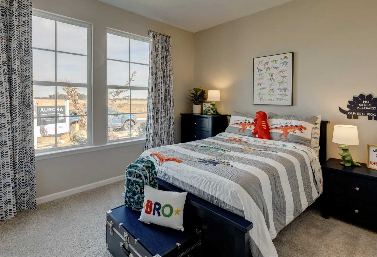 Dinosaur-themed boy's bedroom in The Aurora Davidson Homes design featuring twin bed, posters, toys, and large windows