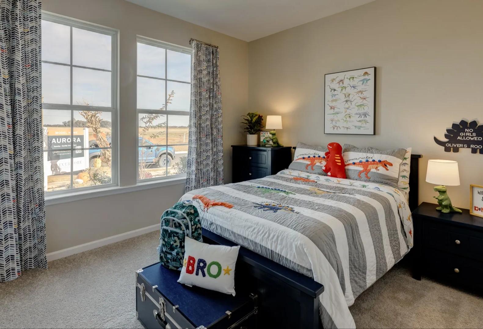 Dinosaur-themed boy's bedroom in The Aurora Davidson Homes design featuring twin bed, posters, toys, and large windows