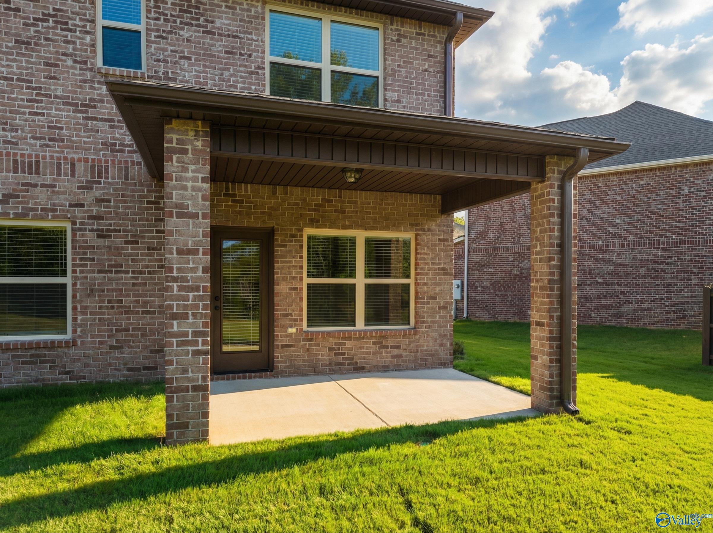 Covered back patio with brick columns and sliding doors overlooking lush green lawn in Davidson Homes The Shelby A, Ricketts Farm, Athens, Alabama