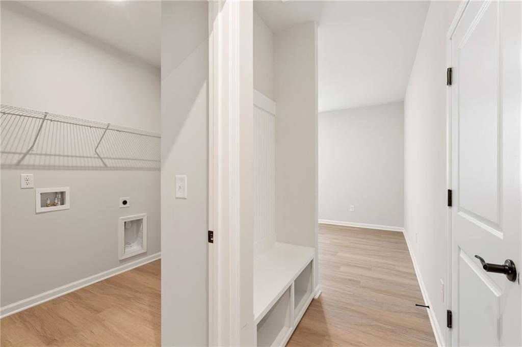 Spacious laundry room with wire shelving, built-in bench and hardwood floors in Davidson Homes The Daphne C, Kelly Preserve, Loganville, GA