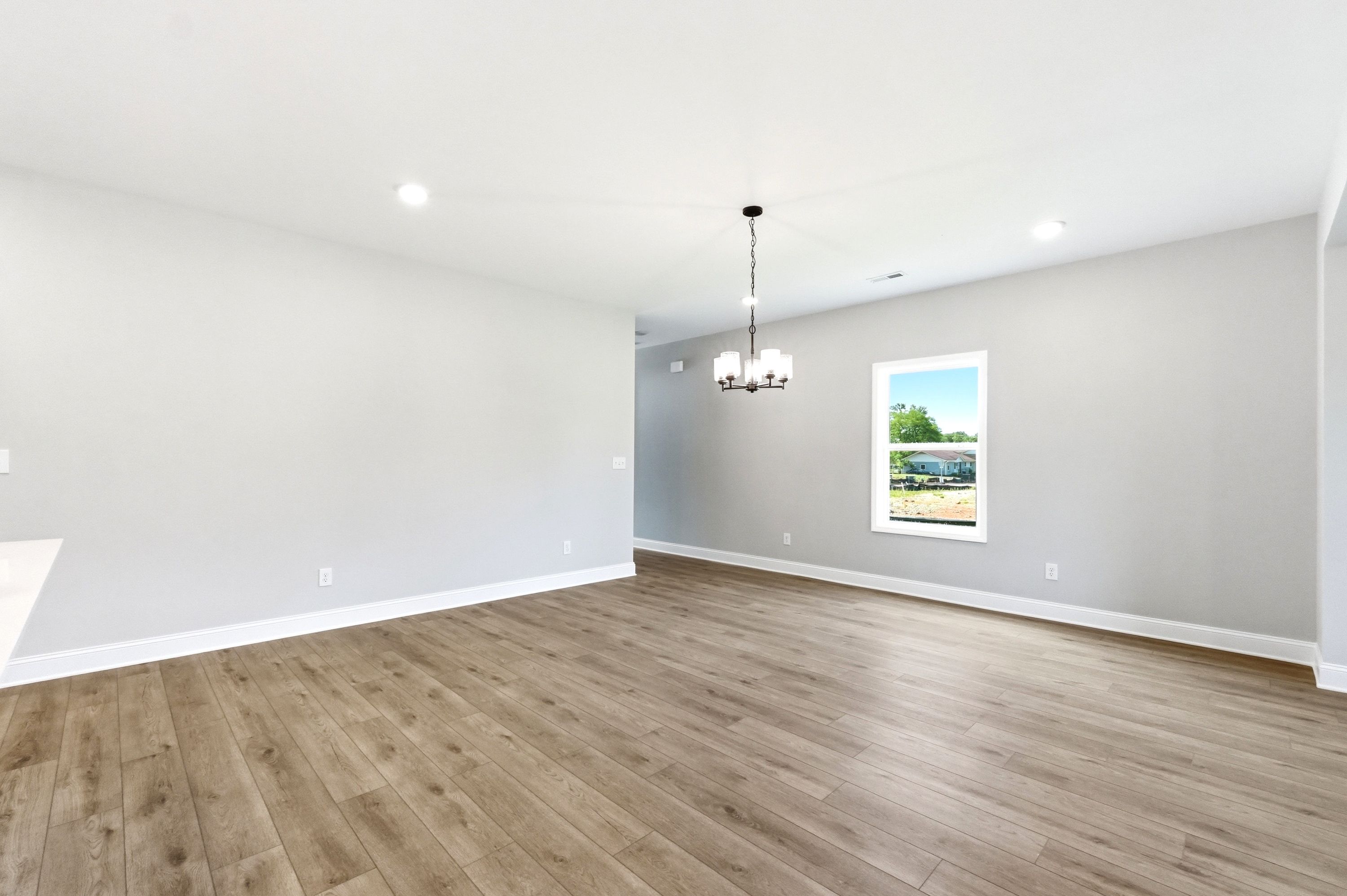 Spacious dining area in The Russell A floor plan featuring wood-style flooring, neutral walls, and a modern chandelier.
