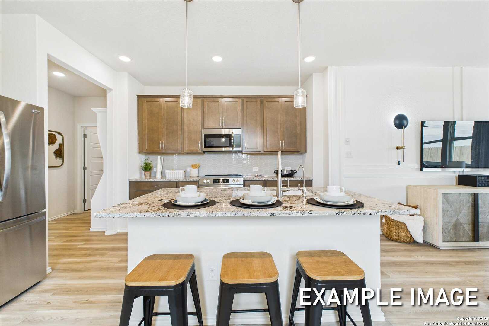 Modern open-concept kitchen with white quartz island, stainless steel appliances, and pendant lights in Davidson Homes The Brazos C, San Antonio