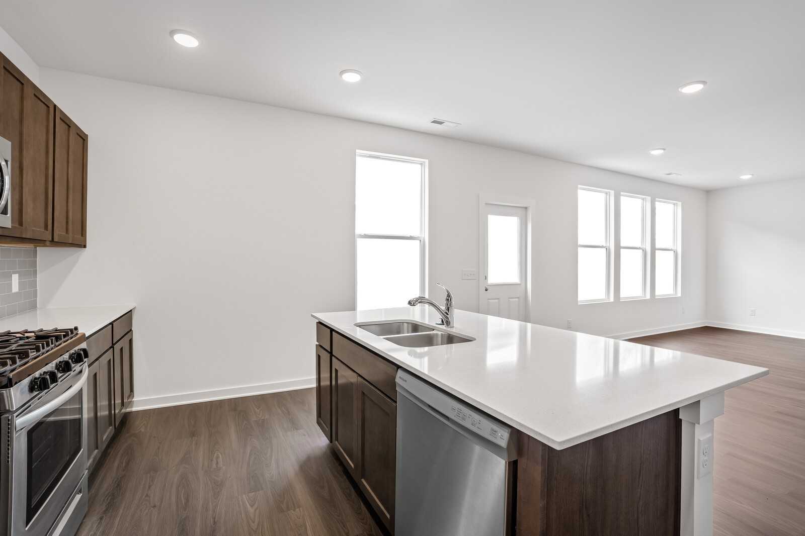 Modern open-concept kitchen with white quartz island, stainless steel appliances, dark cabinets in Davidson Homes The Logan C, White House TN