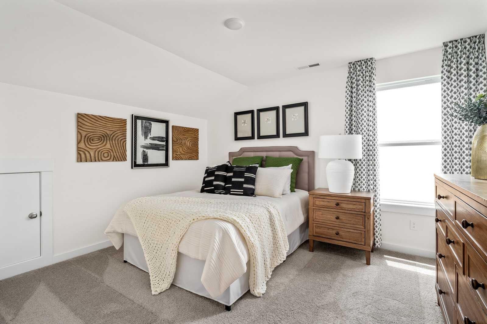 Cozy bedroom at Woods Crossing in Gallatin TN by Davidson Homes with queen bed, neutral bedding, wooden nightstand, abstract wall art