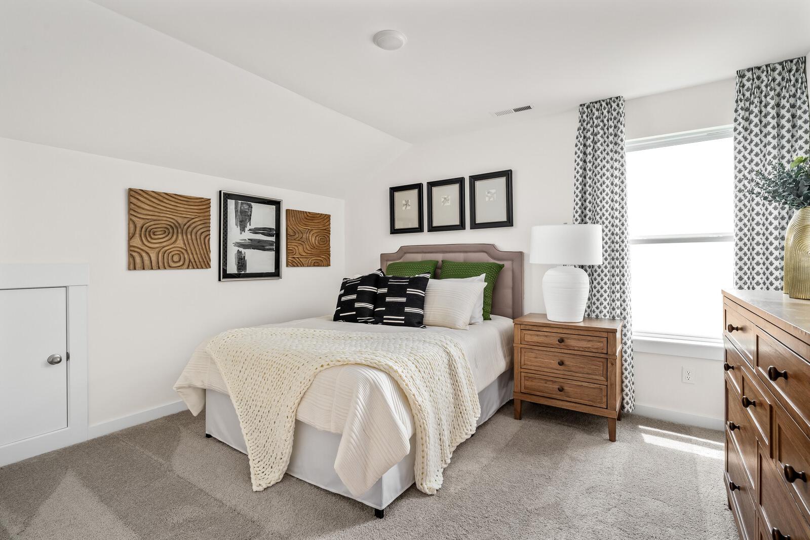 Cozy bedroom at Woods Crossing in Gallatin TN by Davidson Homes with queen bed, neutral bedding, wooden nightstand, abstract wall art
