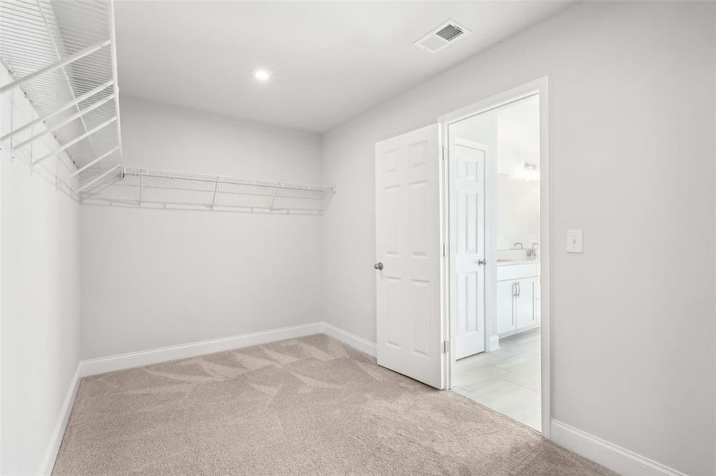 Spacious walk-in closet with wire shelving and double doors to en-suite bath in Davidson Homes The Hickory C, Hoschton, GA