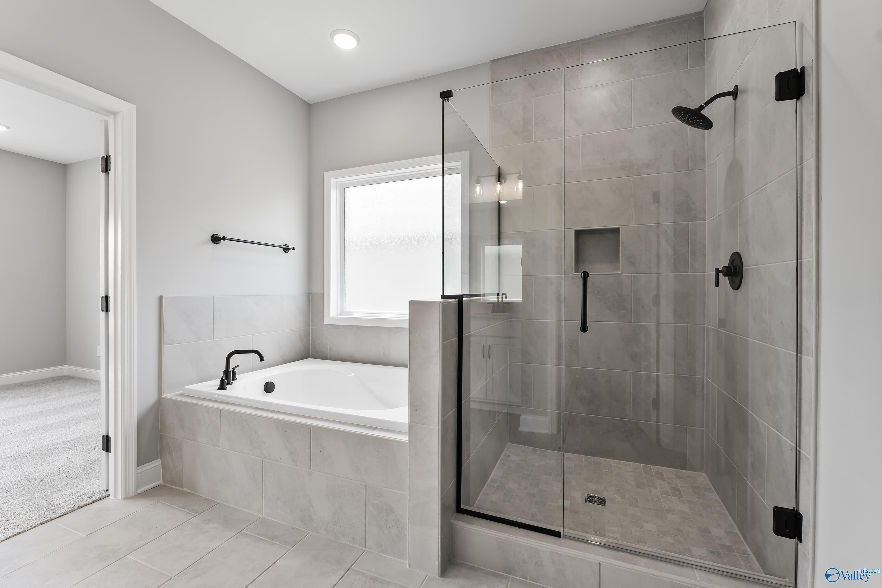 Modern master bathroom featuring glass shower enclosure, soaking tub, and gray tile in Davidson Homes The Montgomery B With Bonus, Toney, Alabama