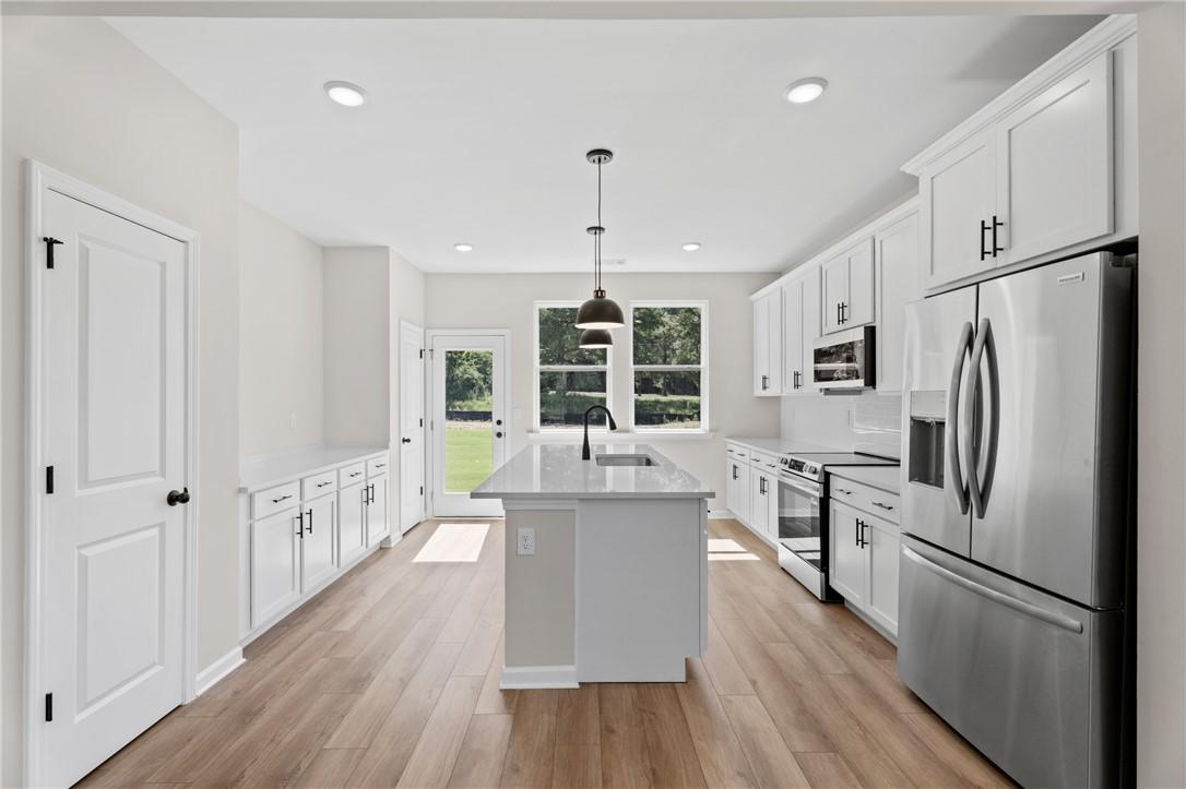 Modern kitchen with white cabinets, center island, and stainless appliances in The Stella C floor plan, Auburn, Alabama.