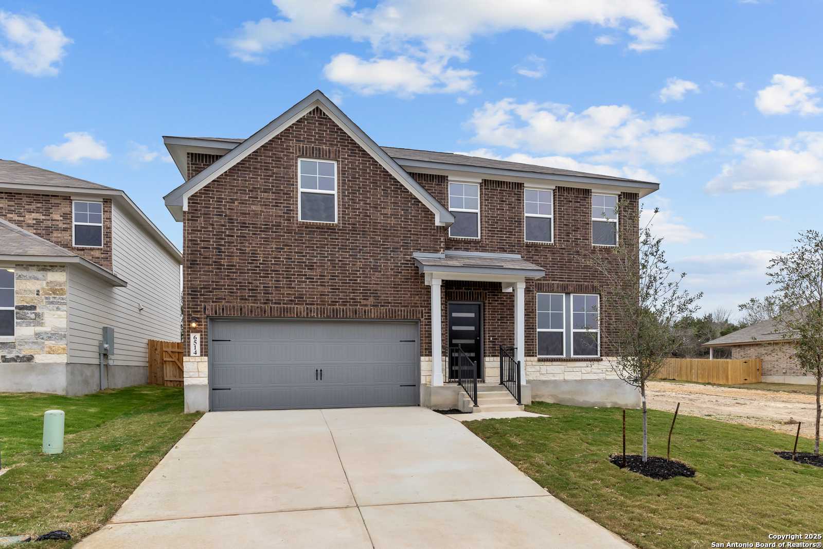 Modern two-story brick home with gabled roof, 2-car garage, covered porch, and landscaped yard in Royal Crest, San Antonio
