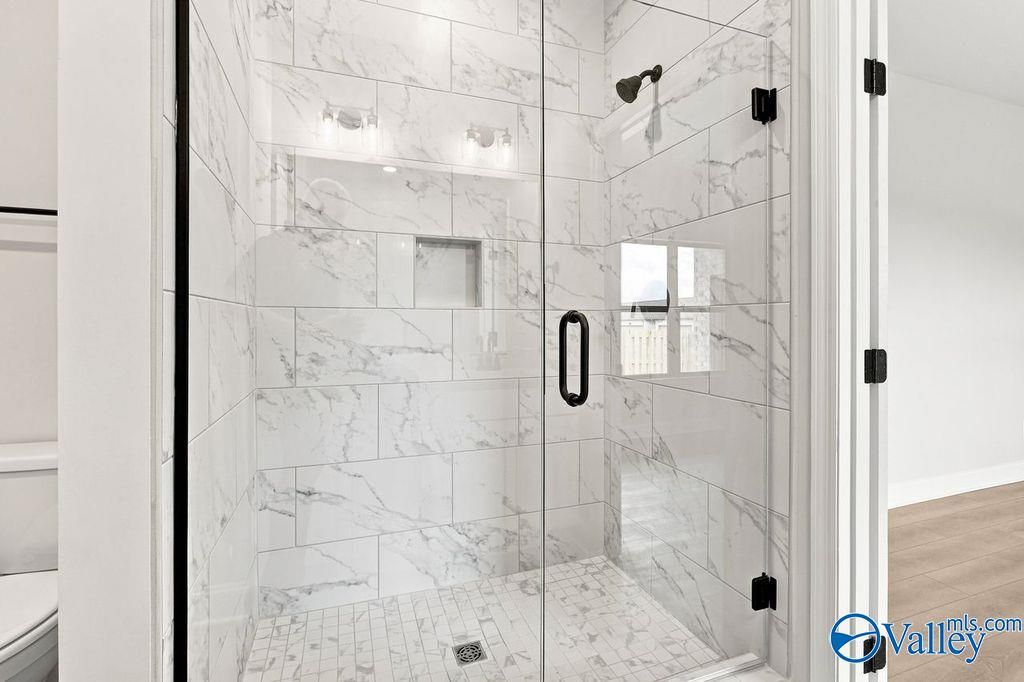 Walk-in shower with white marble-look tile and glass door in The Camilla B floor plan at The Retreat at Cain Park, Hartselle.