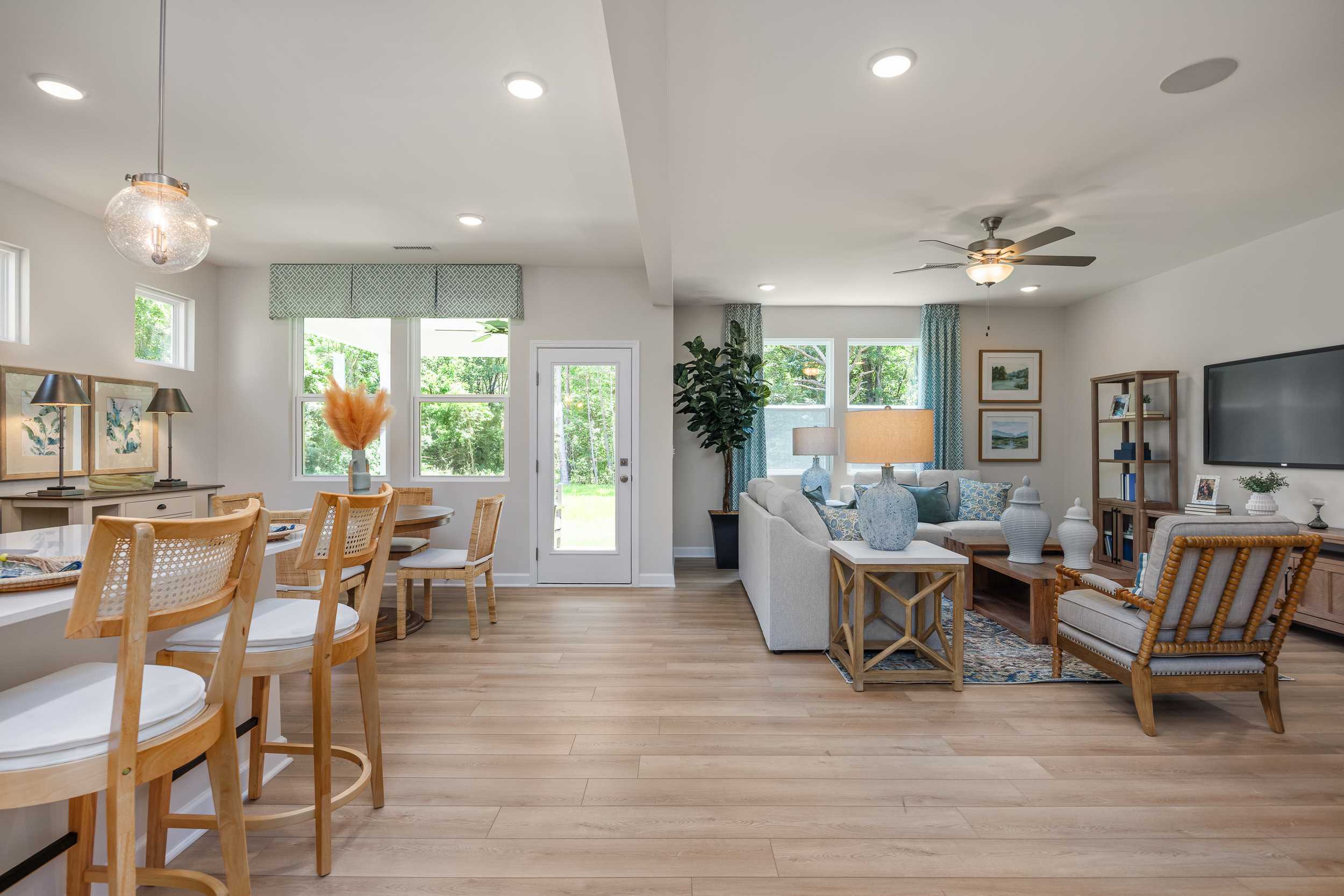 Open-concept living dining kitchen at Retreat at North Main in Lillington NC with hardwood floors, modern sofa, bar stools, and large windows