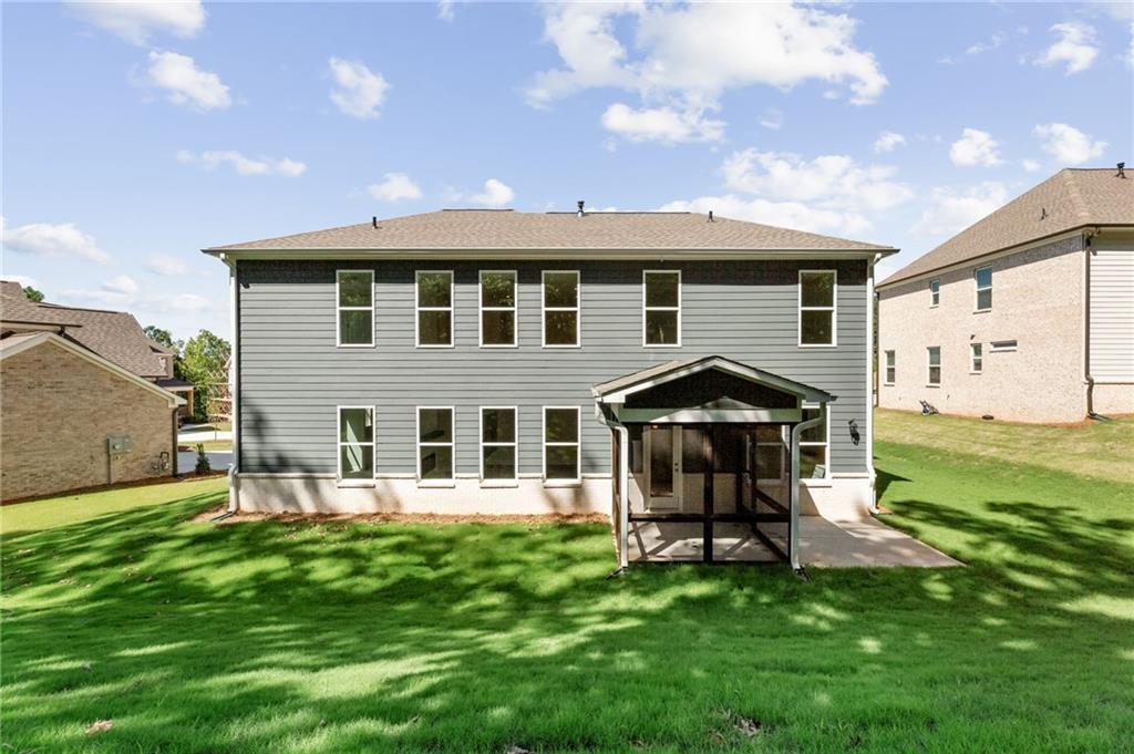 Rear view of The Danbury E 5-bedroom home with screened porch and lush green backyard in Melody Lakeside Estates, Buford, Georgia