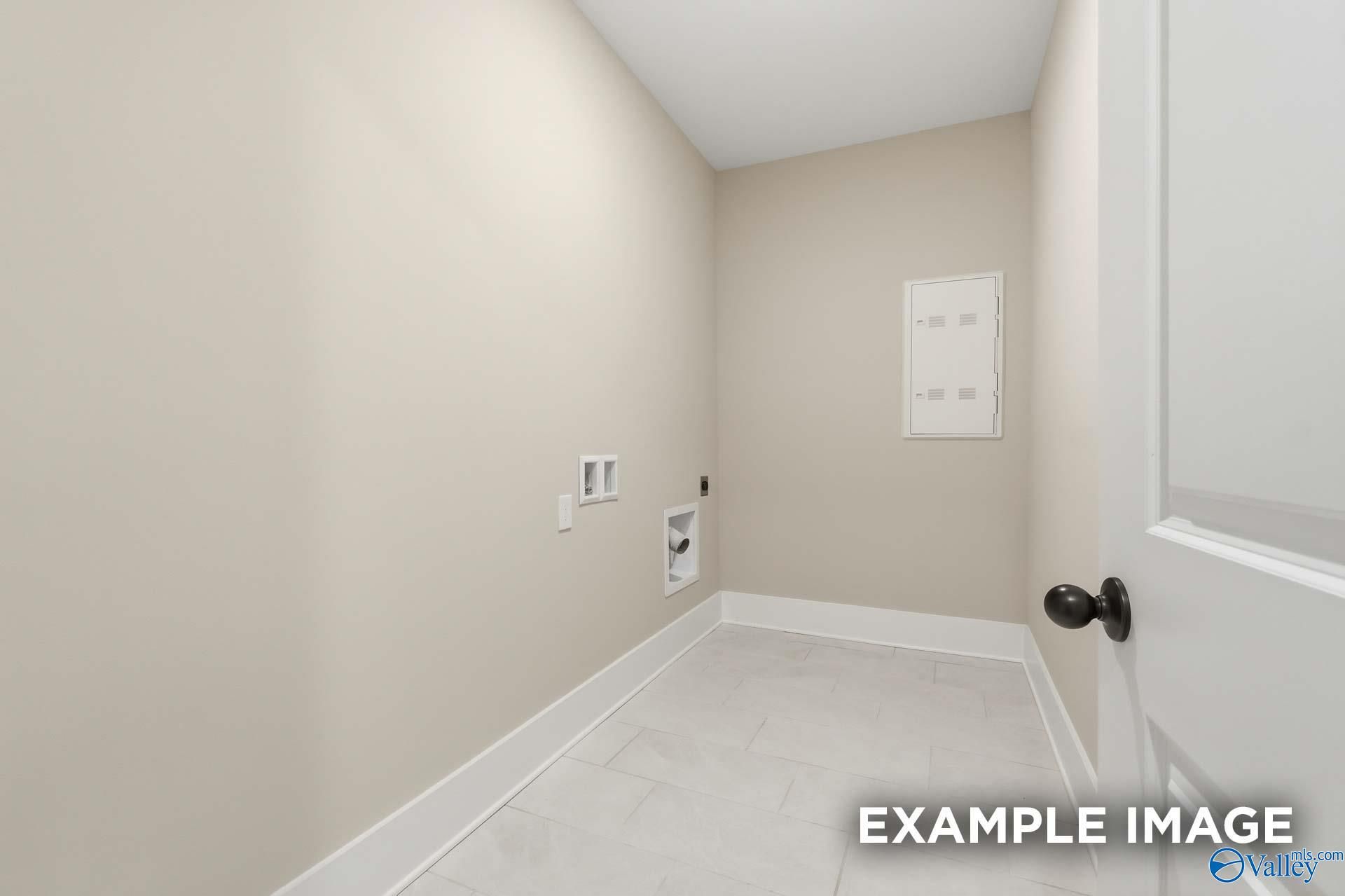 Spacious laundry room with washer-dryer hookups, tiled floor, and beige walls in Davidson Homes The Emory, Decatur, Alabama