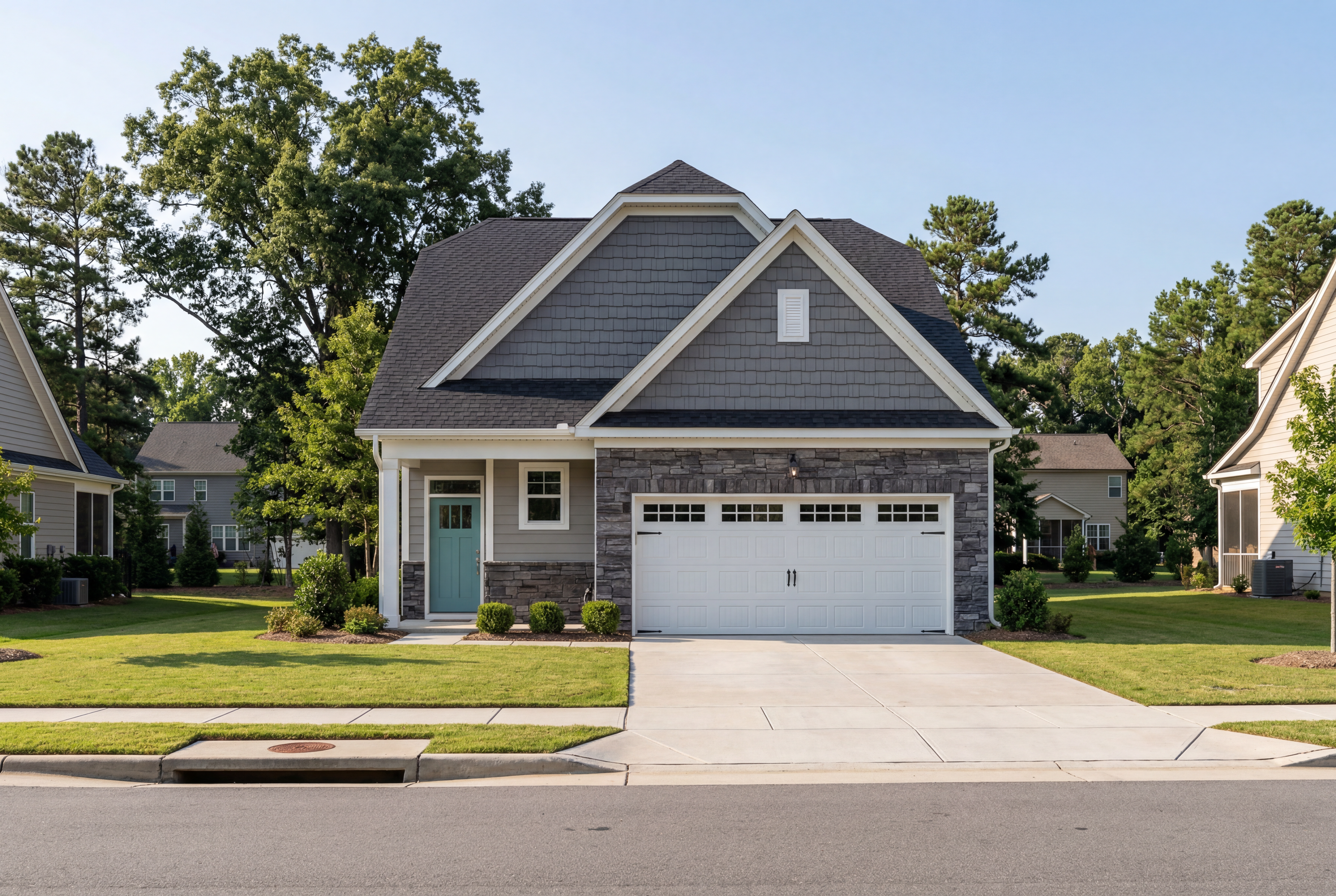 The Carter C single-story home exterior featuring gray gabled roof, stone garage accents, teal door, and landscaped yard in Lillington NC