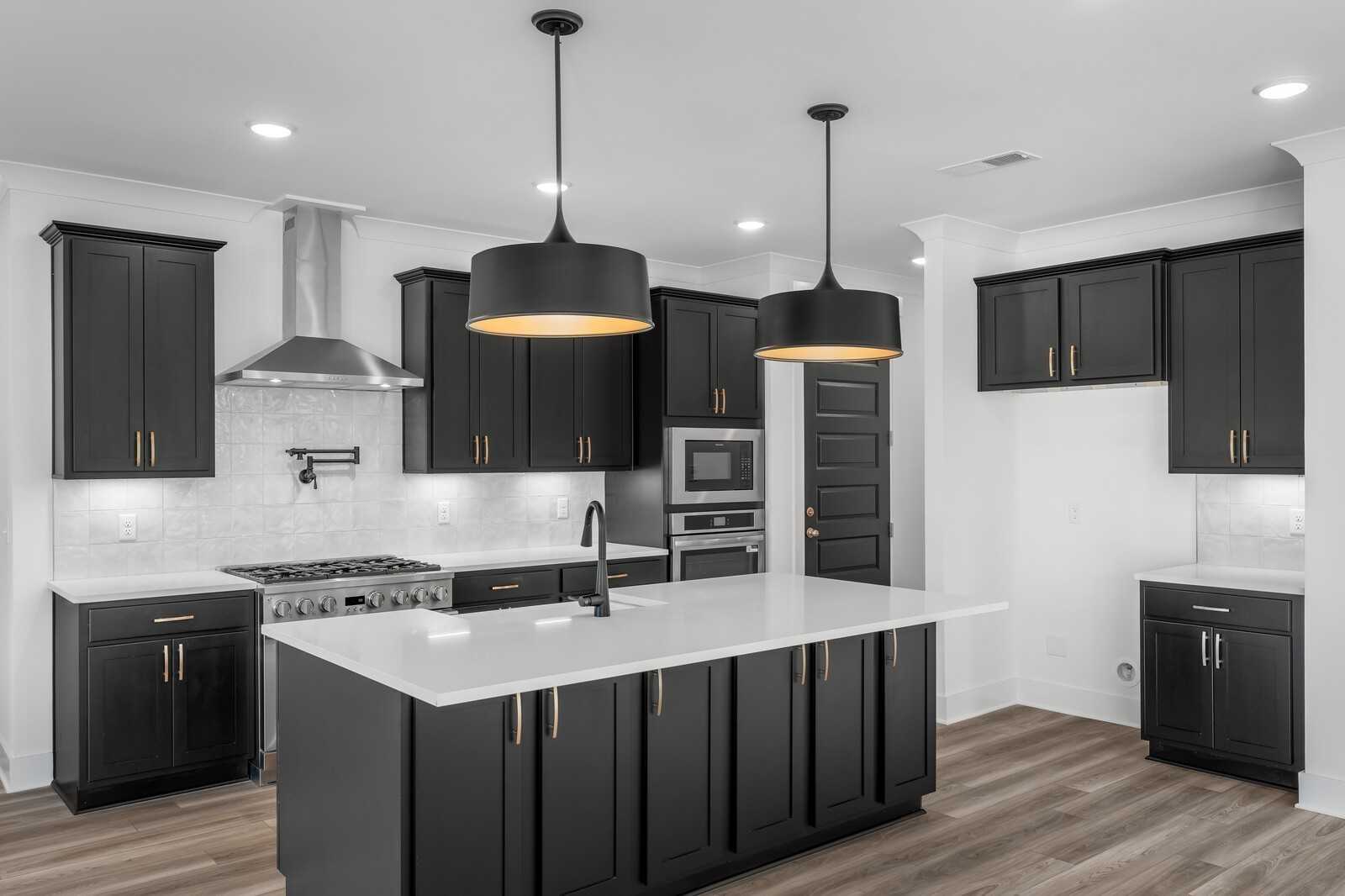 Modern kitchen with black shaker cabinets, white quartz island, stainless steel appliances, and pendant lights in Davidson Homes The Hathaway, Murfreesboro, TN