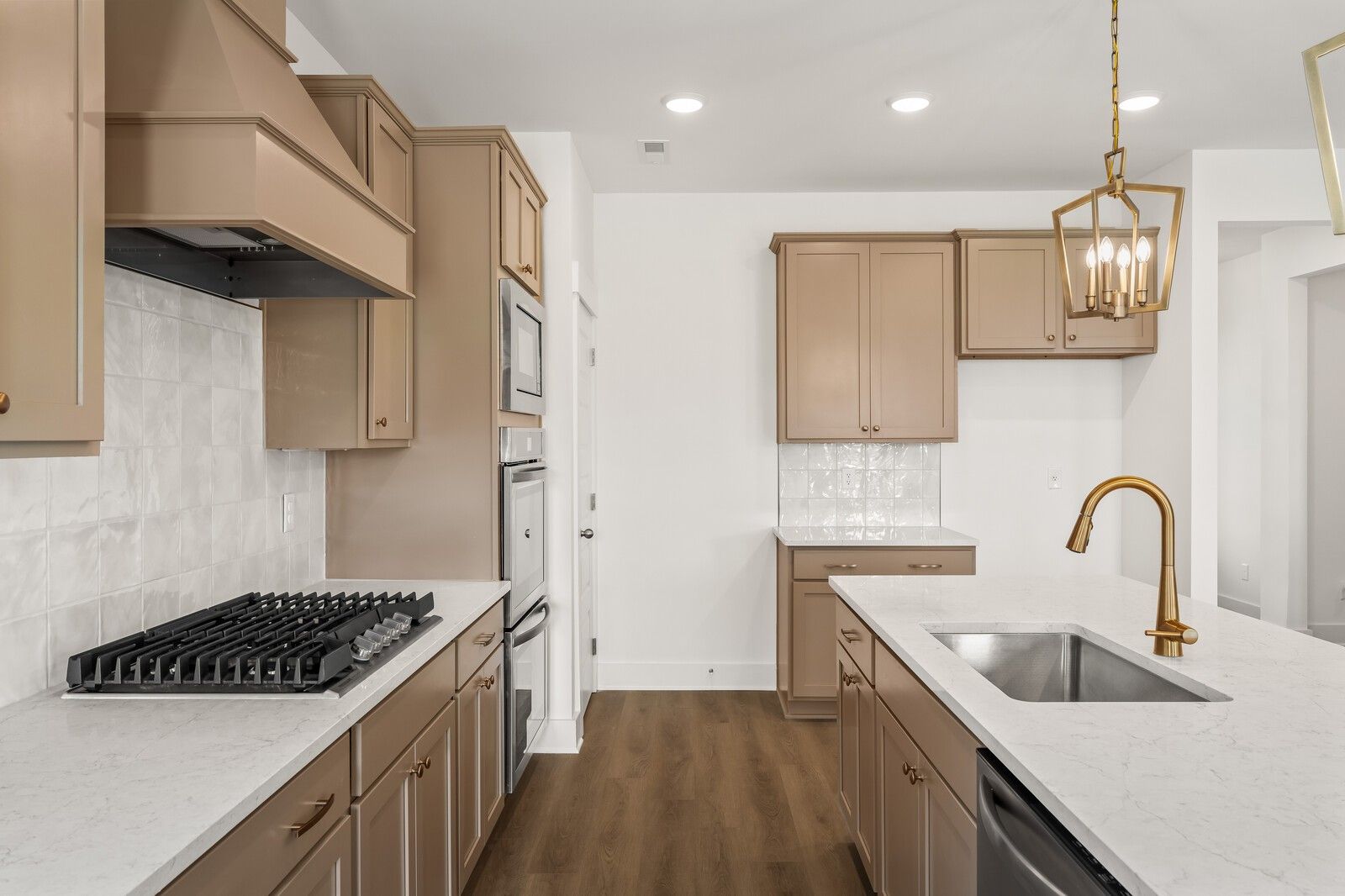 Modern kitchen with beige cabinets, white quartz island, stainless double ovens, gold faucet in Davidson Homes The Ash A, Gallatin, TN