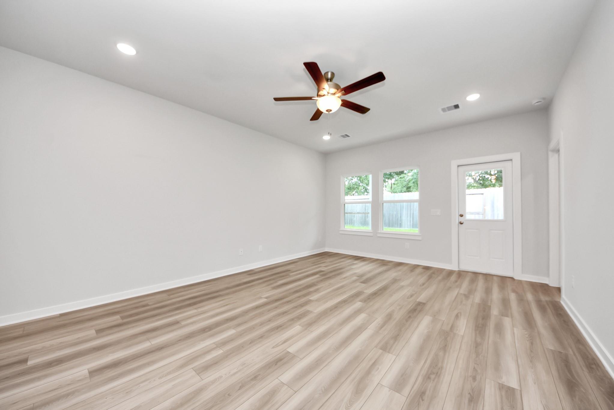 Spacious, light-filled living area with wood-look flooring in The Sabine E floor plan at Windmill Estates, Magnolia, Texas.