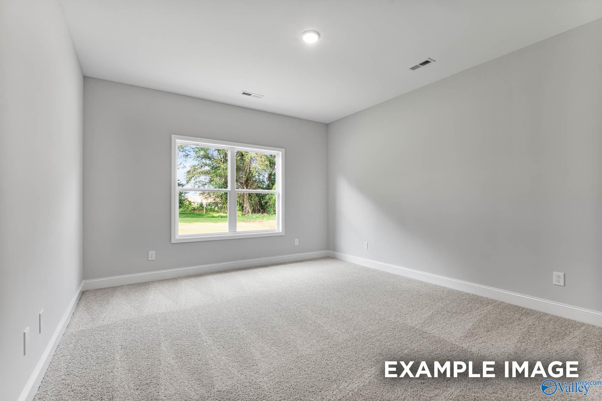 Sunny bedroom with light gray walls, large window to green yard, neutral carpet in Davidson Homes The Daphne C, Arab, Alabama