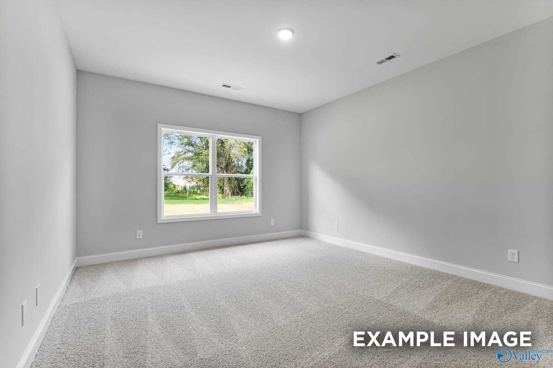 Sunny bedroom with light gray walls, large window to green yard, neutral carpet in Davidson Homes The Daphne C, Arab, Alabama