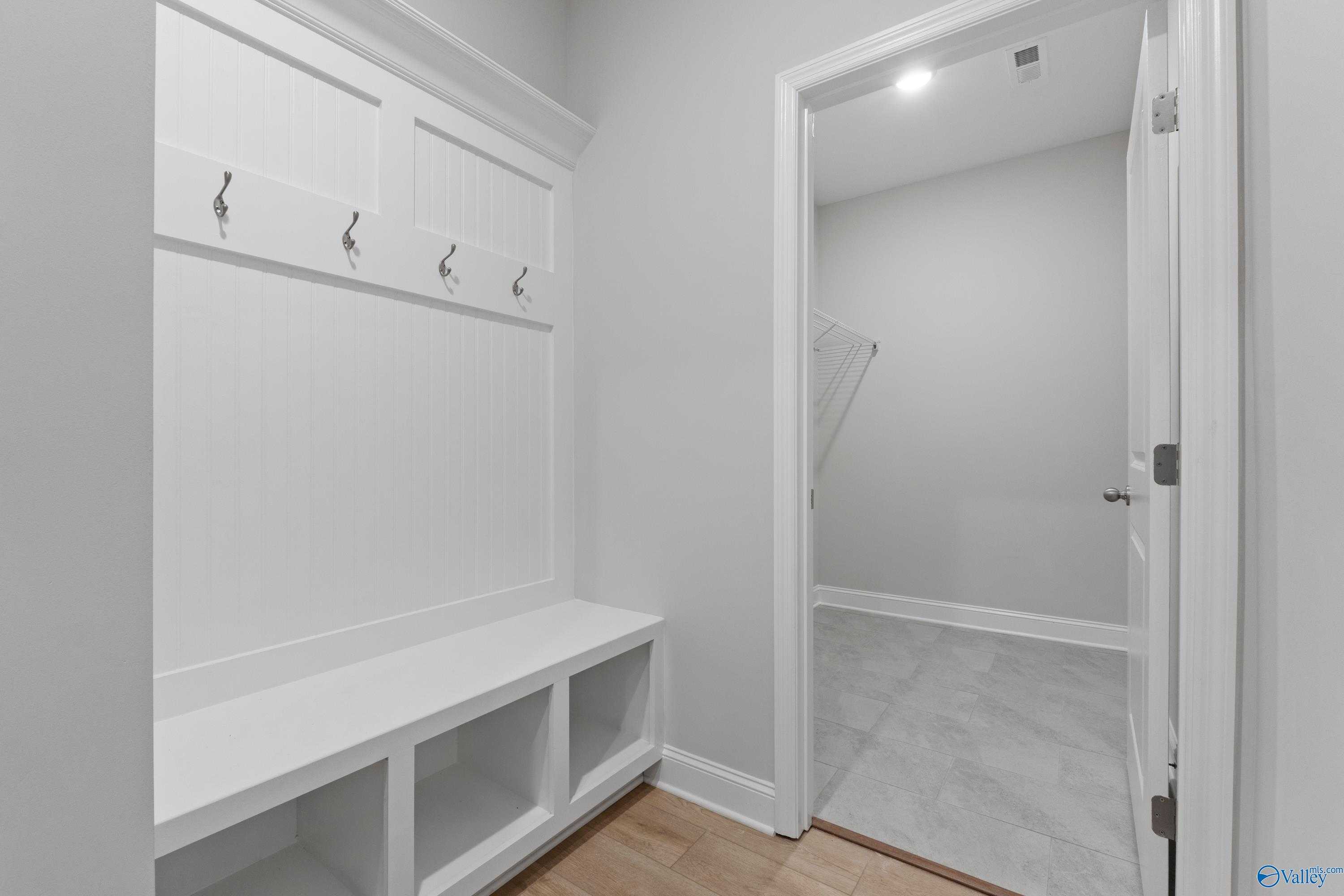 White built-in mudroom with coat hooks, storage bench, and lockers in Davidson Homes The Rockford B, Toney, Alabama
