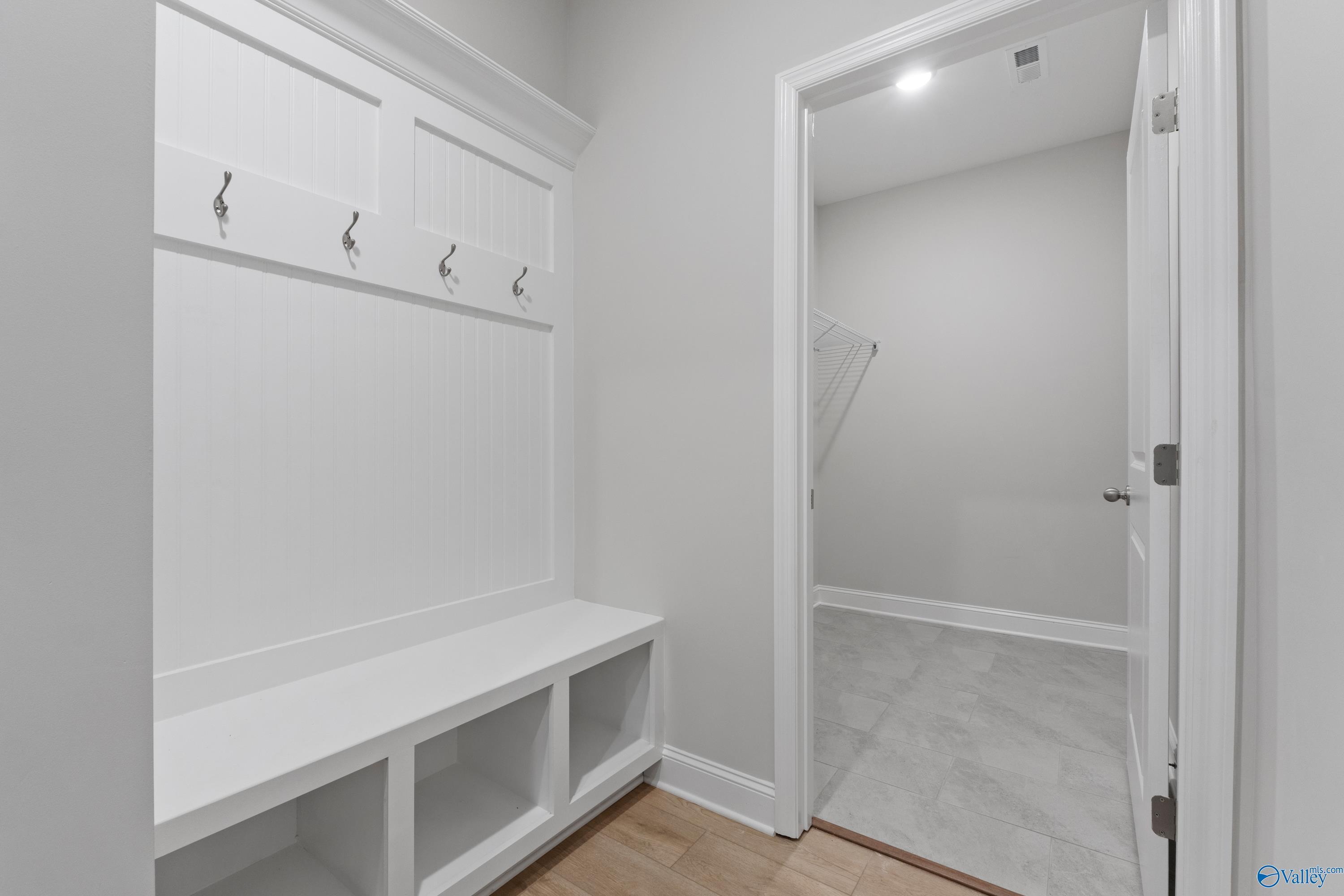White mudroom with built-in coat hooks, storage bench, and cubbies in Davidson Homes The Rockford B with Bonus, Toney, Alabama