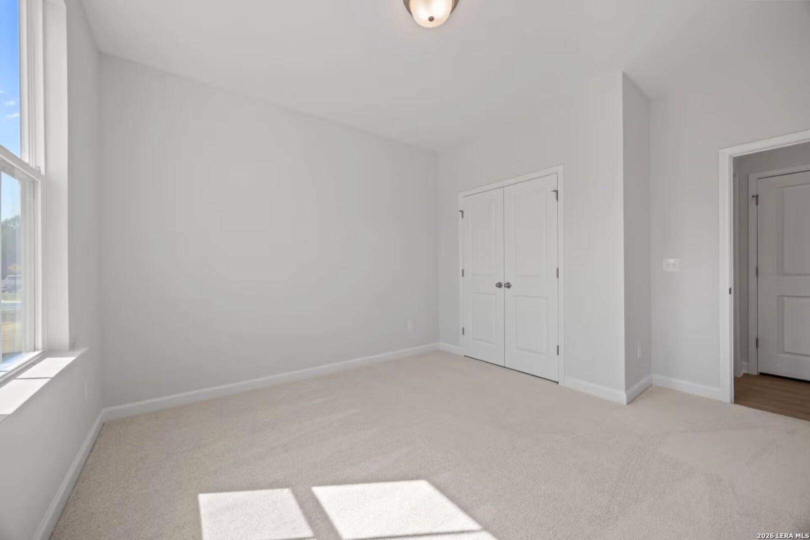 Bright, carpeted bedroom with double-door closet in The Ashport F floor plan at Morgan Meadows, San Antonio, Texas.