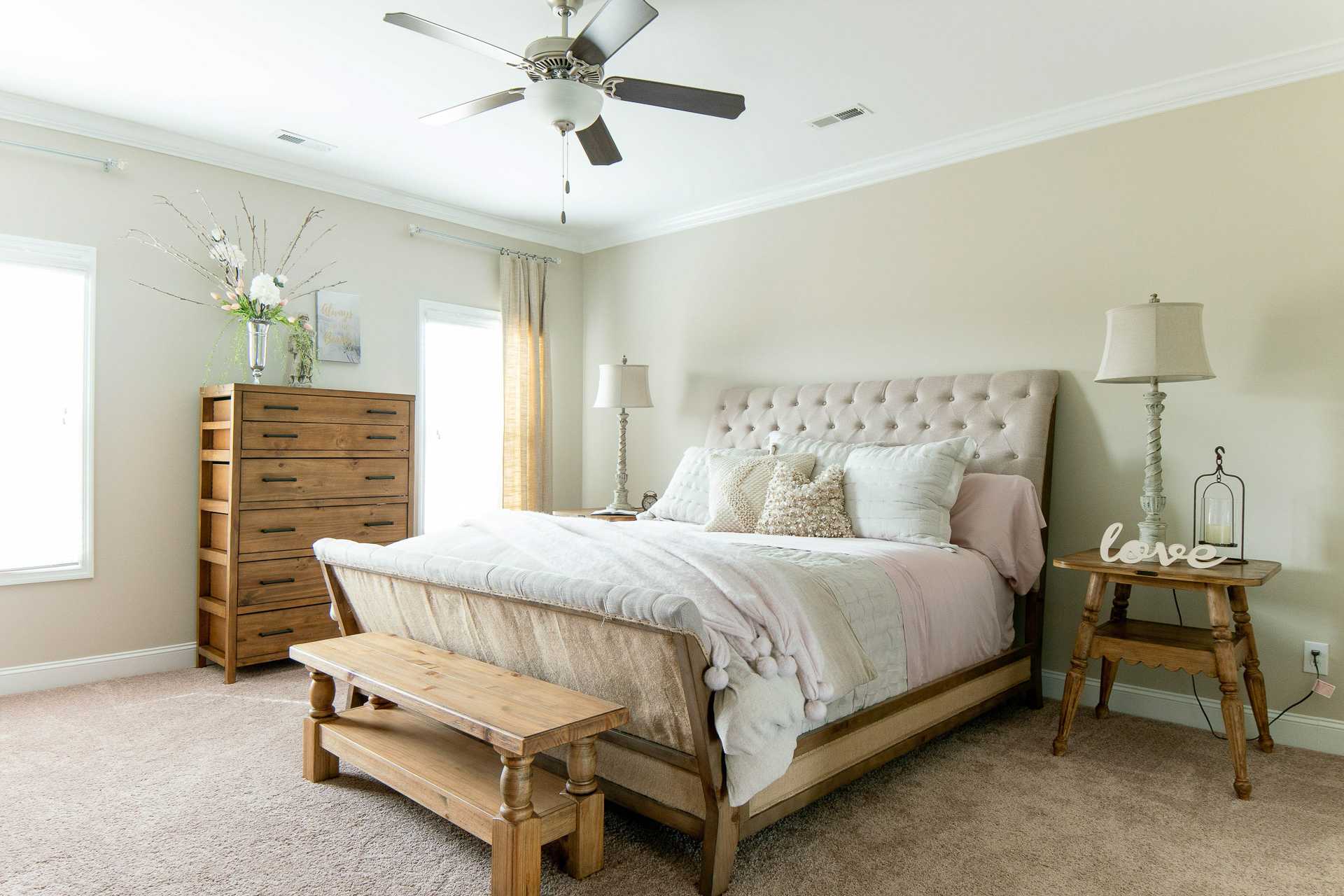 Spacious master bedroom at The Dairy at Oak Grove in South Huntsville AL with tufted upholstered bed, wooden dresser, and beige walls