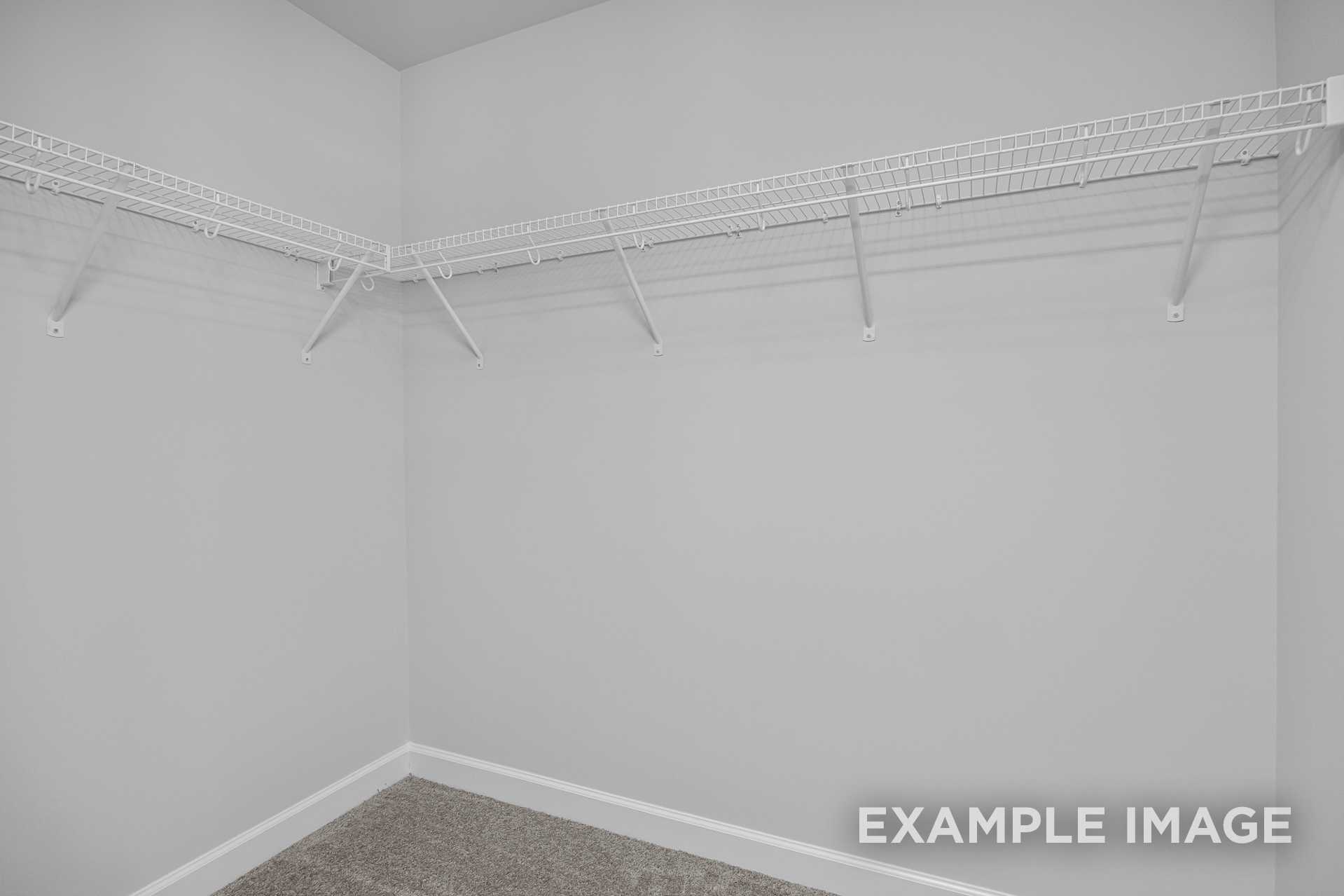Spacious empty walk-in closet in The Adalynn A master suite with white wire shelving and gray walls