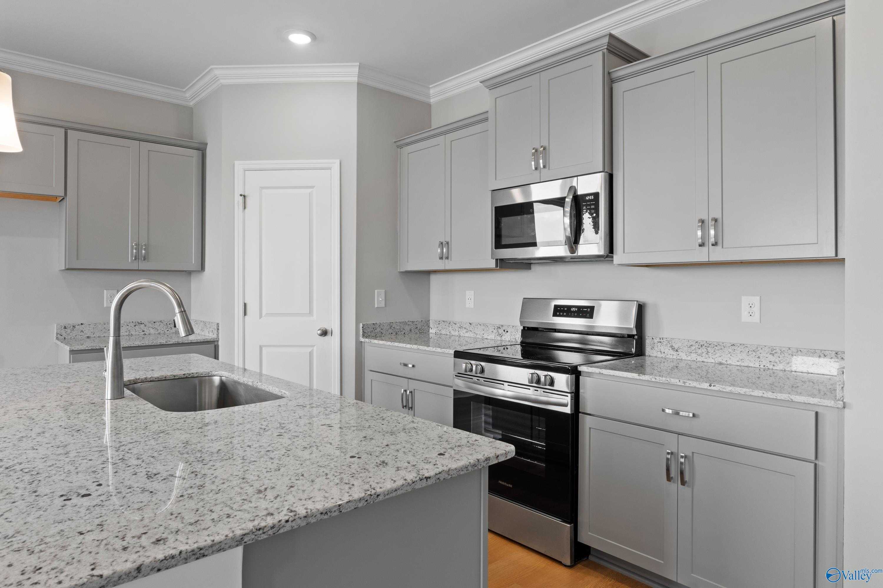 Modern kitchen with gray shaker cabinets, granite island sink, stainless steel appliances in Davidson Homes The Orion, Athens AL