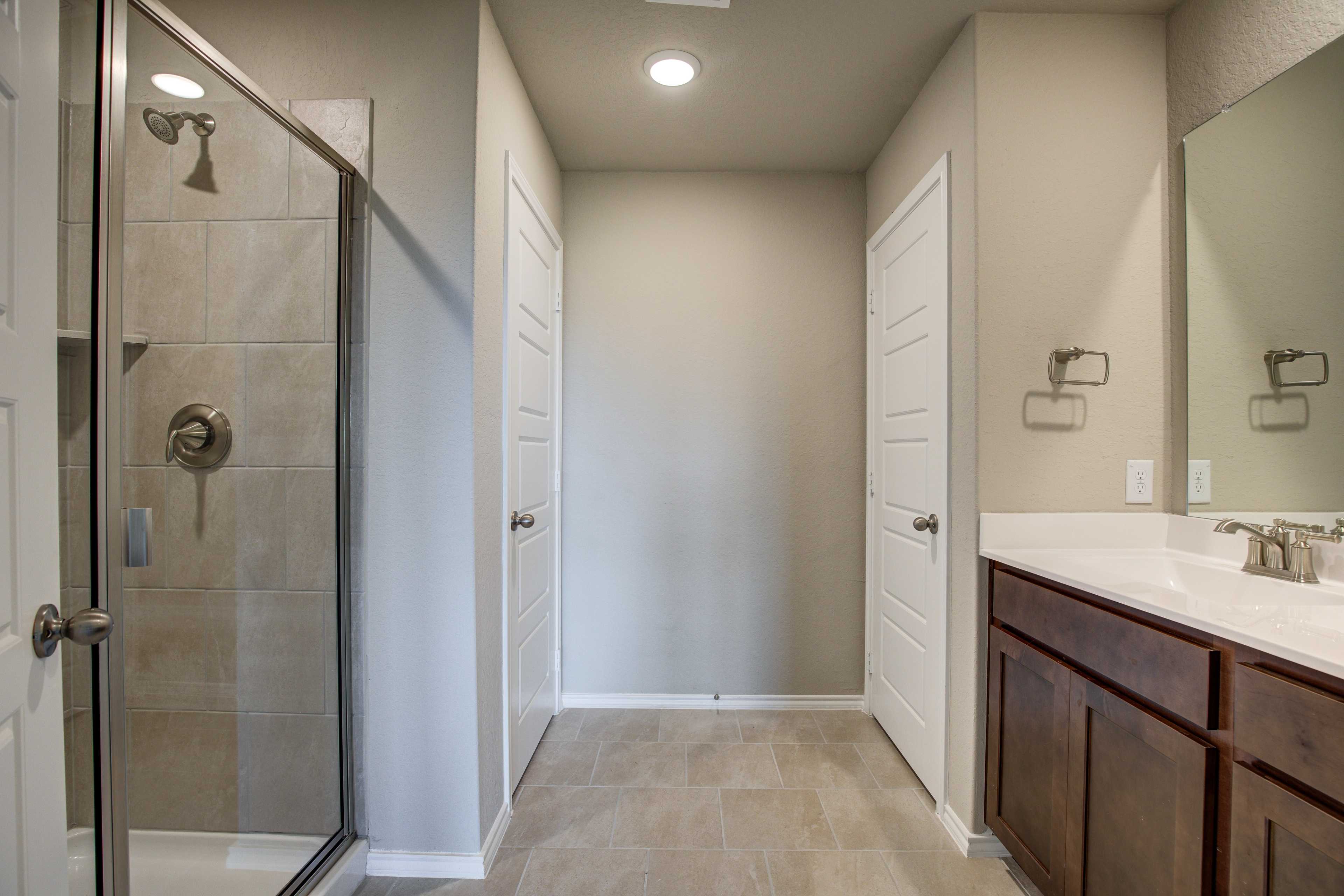Spacious master bathroom in The Murray featuring walk-in shower, double vanity, neutral tones and tile floor