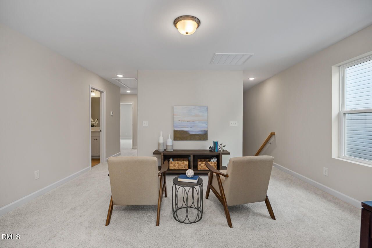 Cozy beige seating area with armchairs, round table, and abstract art in Davidson Homes The Preston A, Lillington, NC