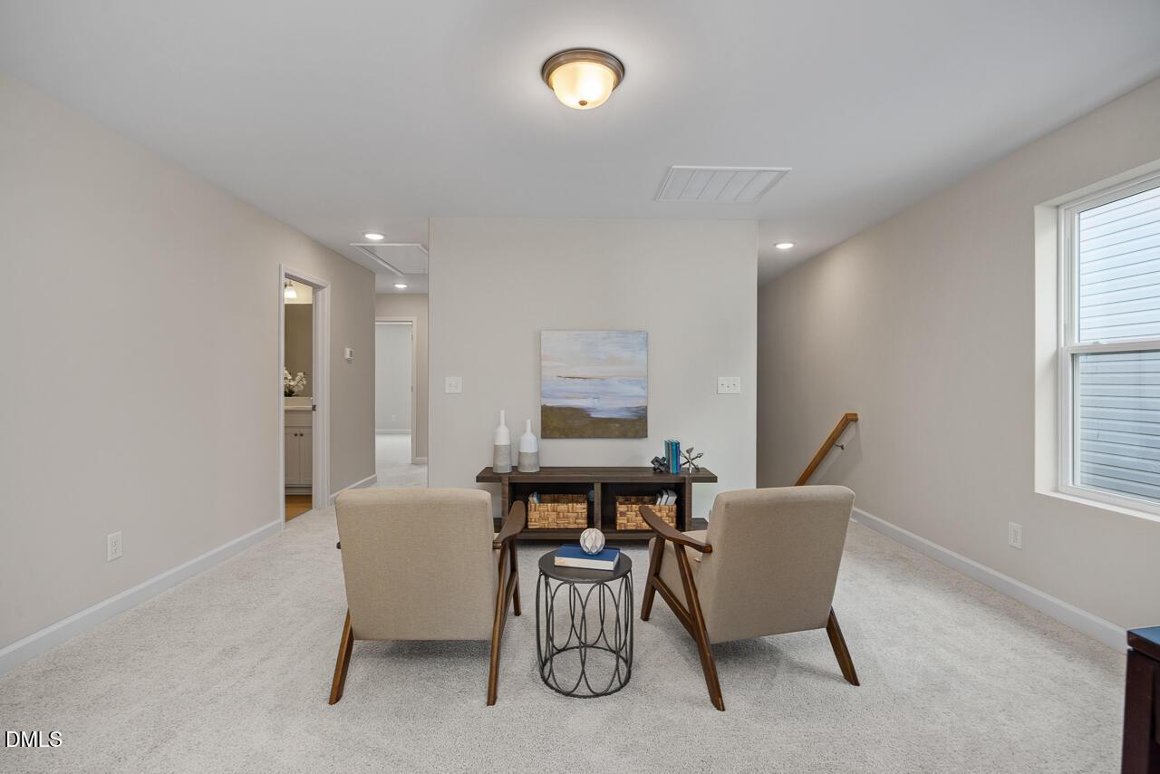 Cozy beige seating area with armchairs, round table, and abstract art in Davidson Homes The Preston A, Lillington, NC