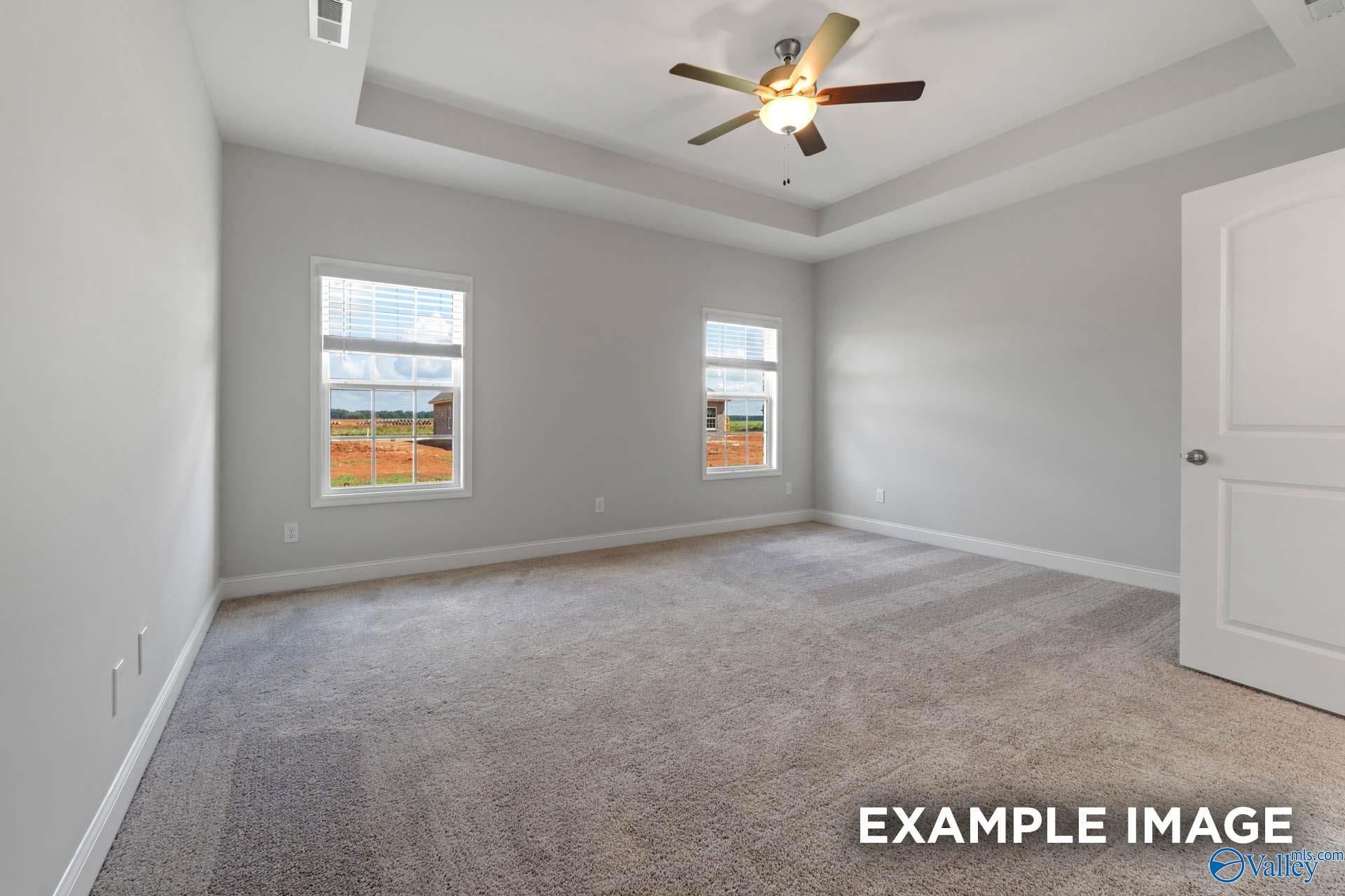 Bright secondary bedroom with large windows, ceiling fan, neutral walls, and carpet in Davidson Homes Harrison B, Decatur AL
