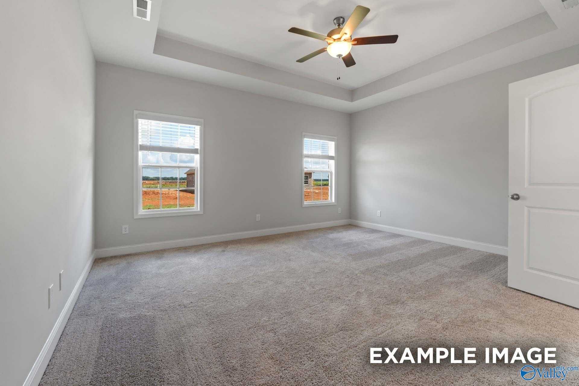 Bright secondary bedroom with large windows, ceiling fan, neutral walls, and carpet in Davidson Homes Harrison B, Decatur AL