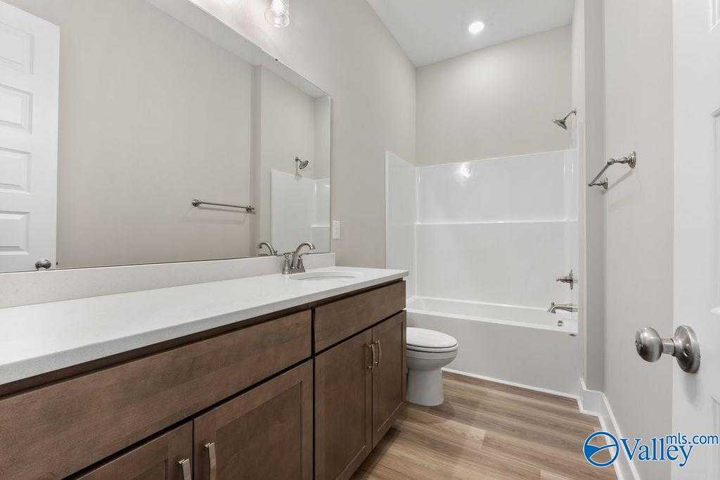 Modern bathroom with white subway tile shower-tub, quartz vanity, brown cabinets in Evermore Homes The Oxford, Owens Cross Roads