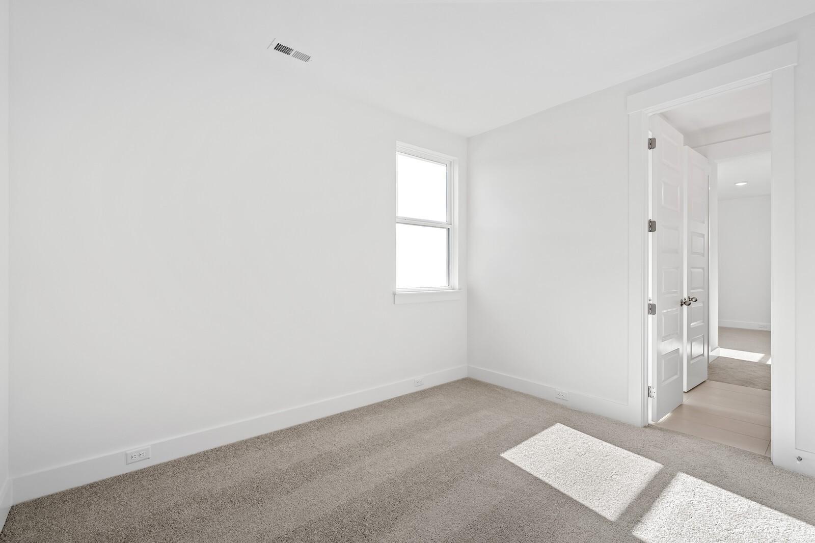 Bright secondary bedroom with beige carpet, white walls, and window in Davidson Homes The Alston A, Murfreesboro TN