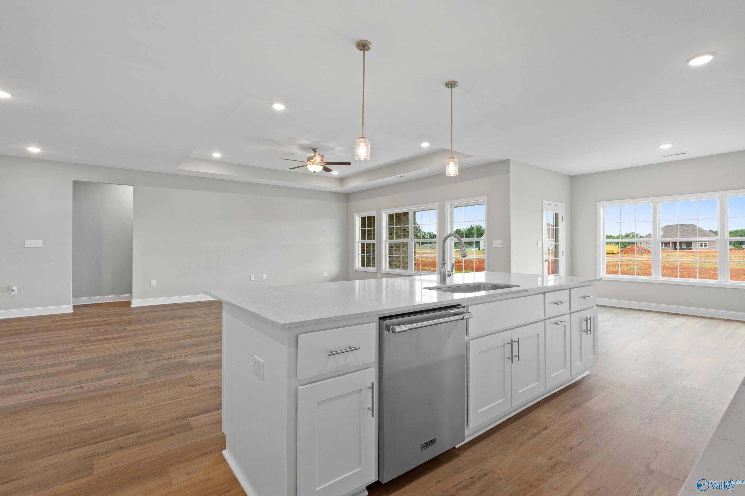 Modern open-concept kitchen with white island, stainless dishwasher, hardwood floors, and large windows in Davidson Homes The Finleigh, Meridianville, Alabama