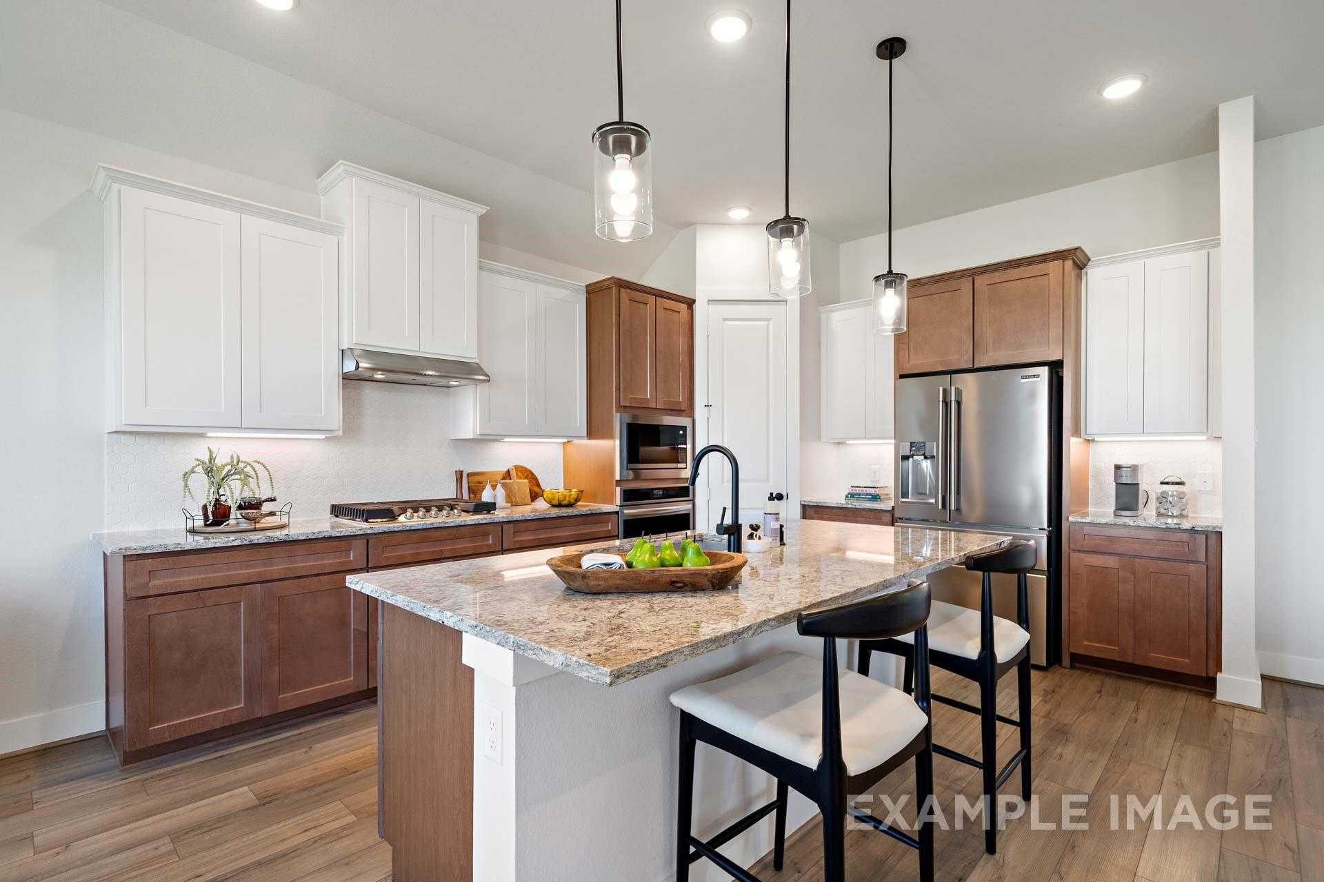 Modern kitchen with granite island, white and wood cabinets, stainless appliances, pendant lights in Davidson Homes The Edward A