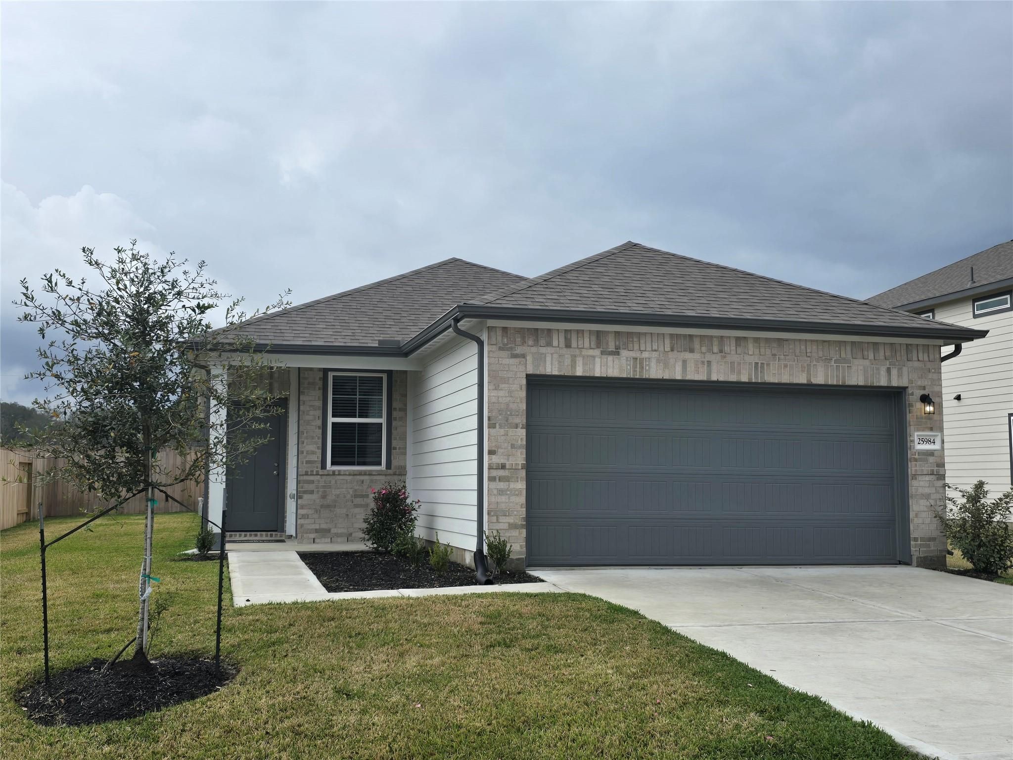 Modern 1-story 4-bedroom home with 2-car gray garage, brick accents, and landscaped front yard in Liberty Estates, Cleveland, Texas by Davidson Homes The Colorado F