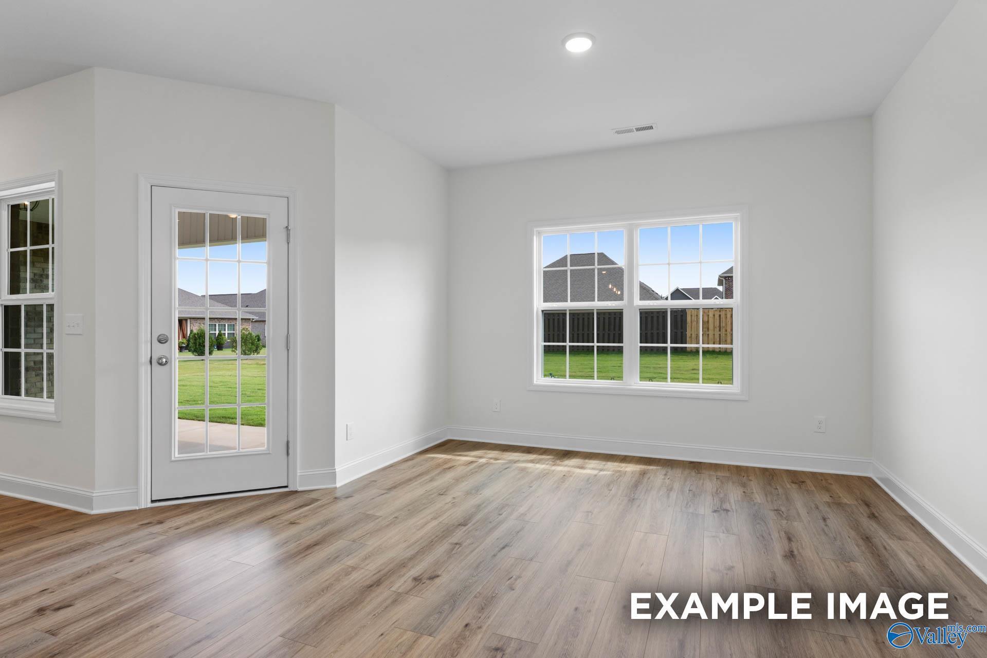 Bright open living room with large windows and French doors to green yard in Davidson Homes The Rockford B, Athens AL
