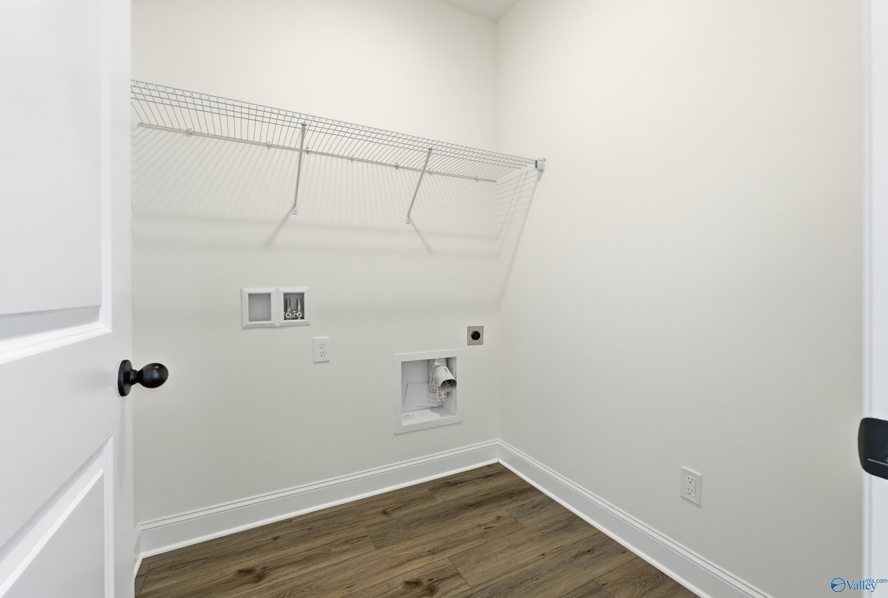 Bright laundry room with wire shelving, washer-dryer hookups, LVP flooring in Davidson Homes The Franklin C, New Market, Alabama