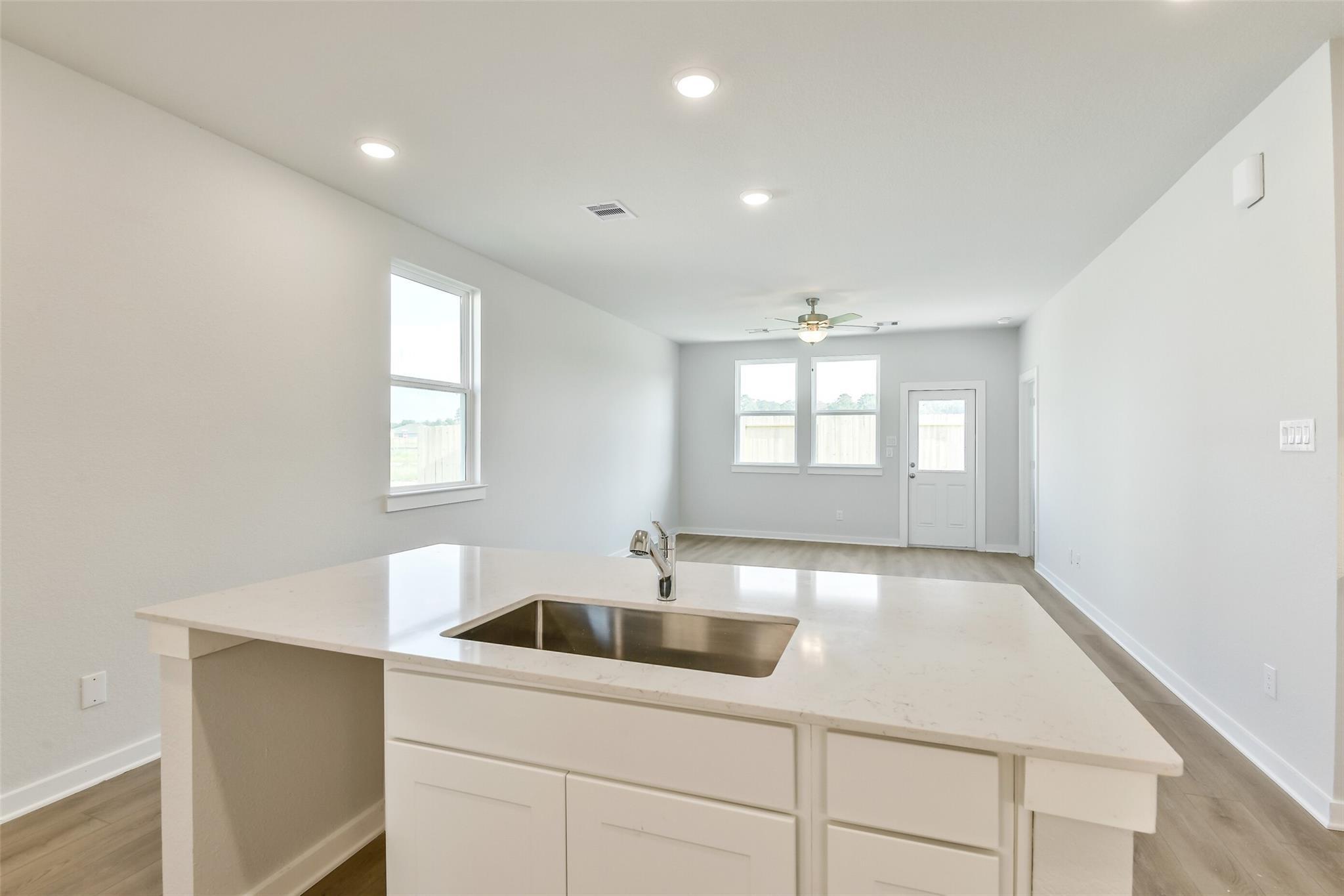 Modern white kitchen island with stainless sink and quartz counters in open-concept space, Davidson Homes Colorado F, Cleveland TX